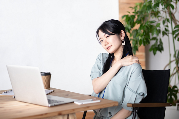 肩を押さえる女性